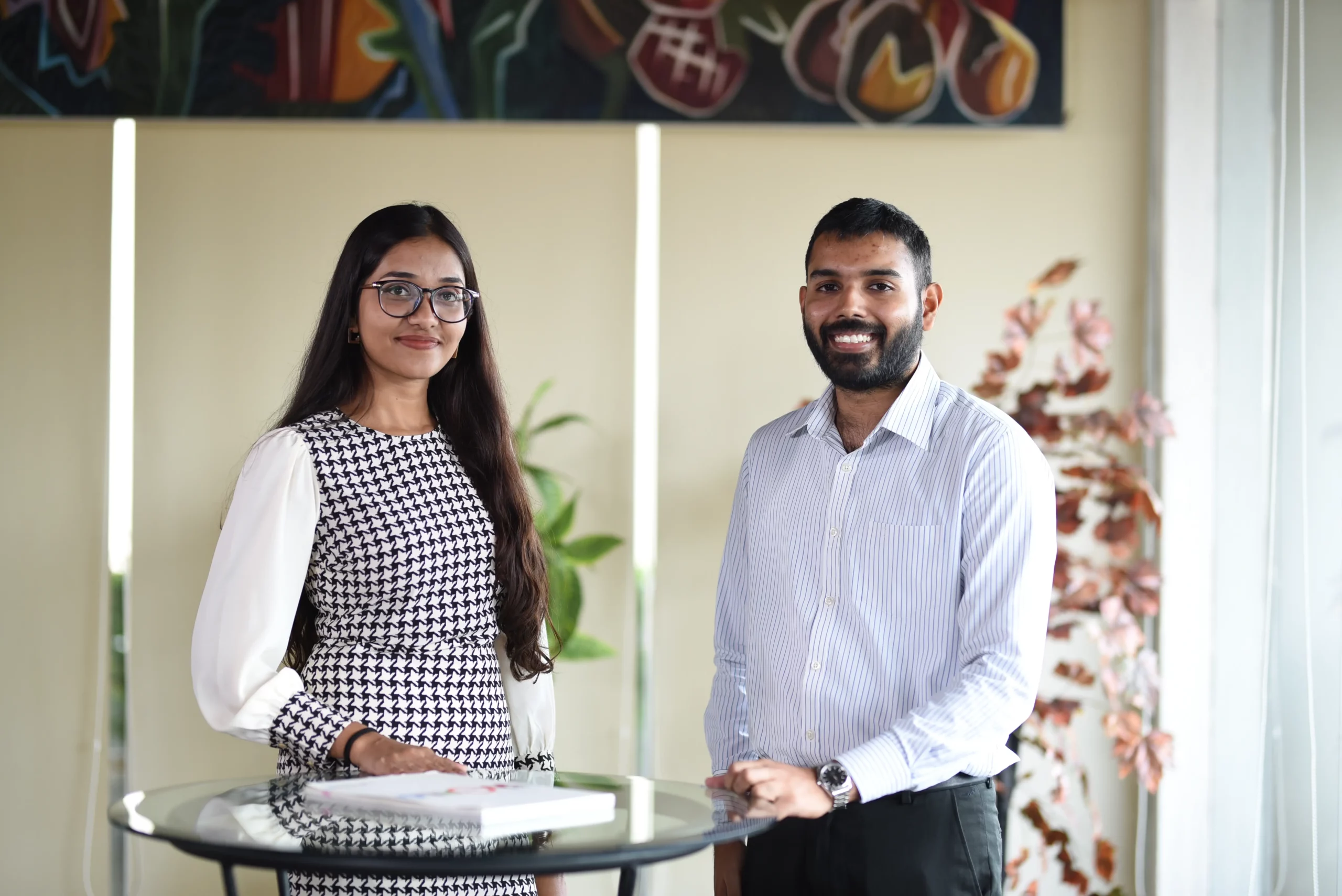A male and female employees near a glass table